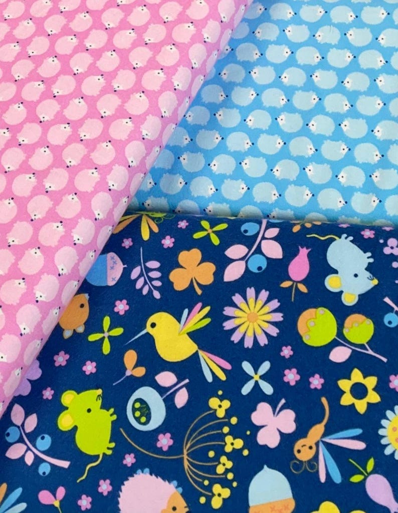 May include: Three fabric swatches with different patterns. The first is pink with a repeating pattern of white hedgehogs. The second is light blue with a repeating pattern of white hedgehogs. The third is dark blue with a repeating pattern of yellow birds, green mice, pink flowers, and green leaves.