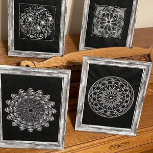 May include: Four framed black and white embroidery designs. The designs are all different, but they all have a similar style. The frames are distressed and have a whitewash finish.