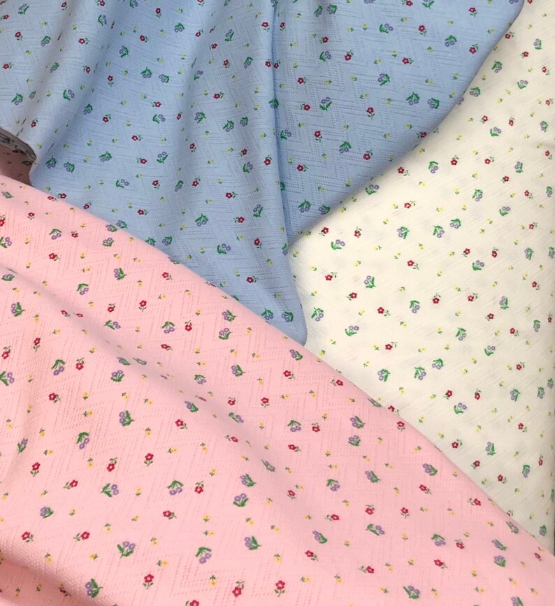 K&ouml;nnte beinhalten: Drei Stoffmuster mit einem kleinen Blumenmuster. Die Muster sind in hellblau, wei&szlig; und rosa.