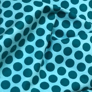 May include: A light blue fabric with a repeating pattern of teal blue polka dots.