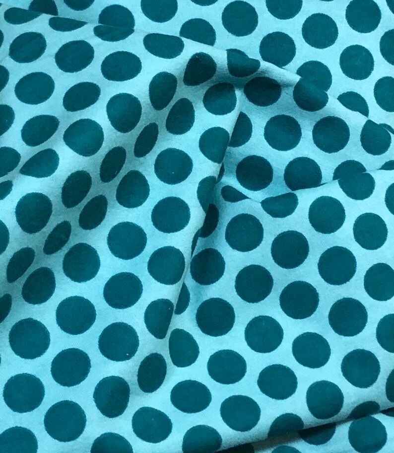 May include: A light blue fabric with a repeating pattern of teal blue polka dots.