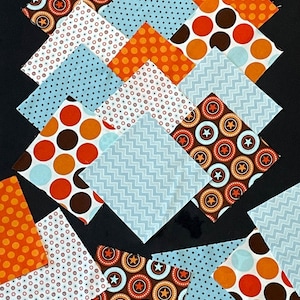 May include: Assortment of fabric squares in various patterns and colors, including orange, brown, blue, and white. The patterns include polka dots, stars, zigzags, and circles.