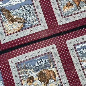 May include: A red and white fabric with a repeating pattern of small squares. The fabric features three different scenes with a mountain range, a lake, and animals. The first scene shows a bald eagle flying over a mountain range. The second scene shows a herd of elk in a lake. The third scene shows a bison standing in a field.
