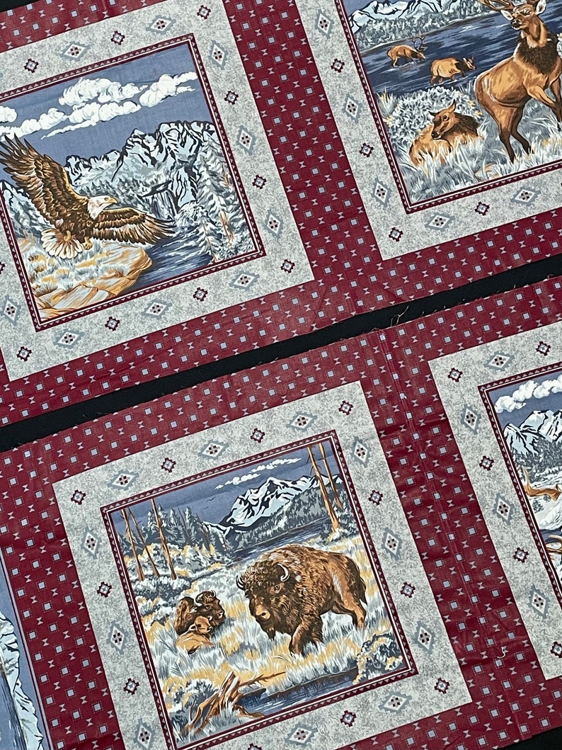 May include: A red and white fabric with a repeating pattern of small squares. The fabric features three different scenes with a mountain range, a lake, and animals. The first scene shows a bald eagle flying over a mountain range. The second scene shows a herd of elk in a lake. The third scene shows a bison standing in a field.