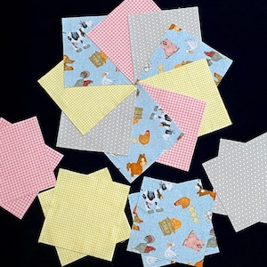 May include: A collection of fabric squares in various patterns, including pink and white gingham, yellow and white gingham, gray with a white dot pattern, and blue with a farm animal print. The squares are arranged in a circular pattern.