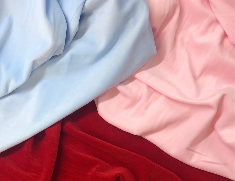 May include: A close-up of three fabric swatches. The swatches are a light blue, a pink, and a deep red.