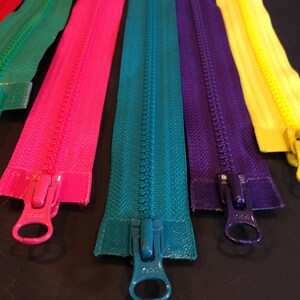 May include: Assortment of colorful zipper tapes with metal sliders. The zippers are in the colors red, green, pink, teal, purple, and yellow.