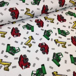 May include: White fabric with a repeating pattern of yellow, red, and green toy construction vehicles. The vehicles are all facing the same direction and have the text "TRACTOR" printed on them.