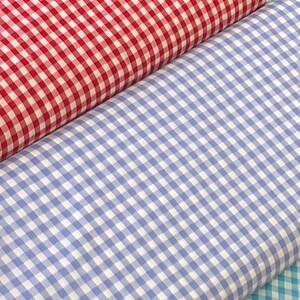 May include: Three rolls of gingham fabric in red, blue, and turquoise. The fabric has a checkered pattern.