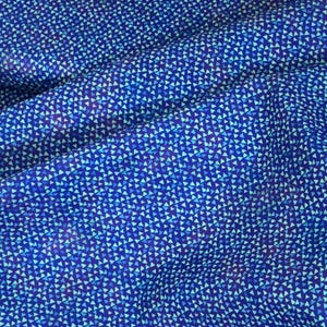 May include: Close-up of a blue fabric with a repeating pattern of small, light blue and dark blue triangles. The fabric has a slightly textured appearance, with folds and shadows adding depth to the design. The overall effect is a modern, geometric textile.