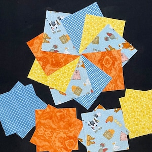 May include: A collection of nine fabric squares in various patterns, including blue gingham, yellow floral, and orange with a marbled design. The squares are arranged in a circular pattern, with the center square featuring a blue background with farm animals.