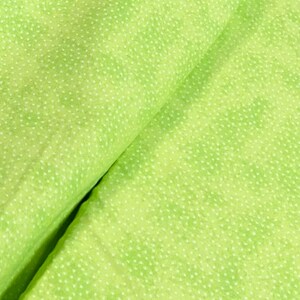 May include: A close-up of a green fabric with a white polka dot pattern. The fabric is folded in half, showing the pattern on both sides.