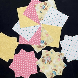 May include: Assortment of fabric squares in pink, yellow, and white with different patterns, including polka dots, stars, and bears.