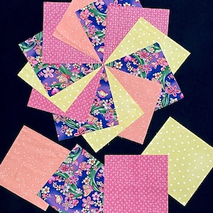 May include: A set of 12 fabric squares in pink, yellow, and blue floral patterns. The squares are arranged in a circular pattern with the floral patterns facing outwards.