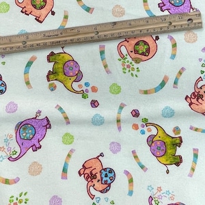 May include: White fabric with a repeating pattern of colorful elephants blowing bubbles. The elephants are decorated with flowers, stars, and geometric shapes. The background is a light blue color.