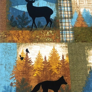 May include: A fabric panel featuring a woodland scene with a black silhouette of a deer, fox, and birds. The design includes pine trees, mountains, and plaid patterns in shades of blue, brown, and green.