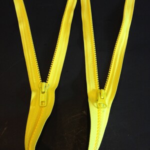 May include: Two yellow zippers with metal sliders. The zippers are laid out in a W shape.