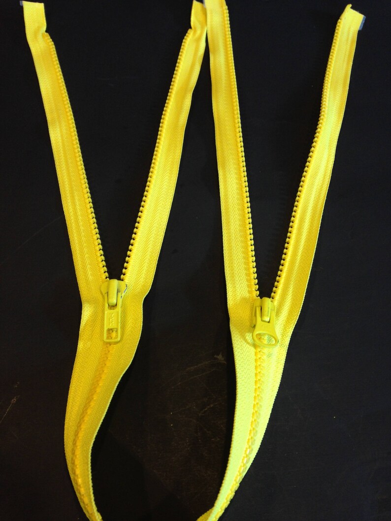 May include: Two yellow zippers with metal sliders. The zippers are laid out in a W shape.