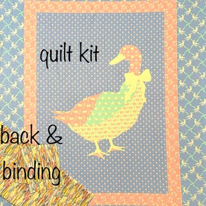 May include: Quilt kit featuring a duck silhouette on a blue background with a white polka dot pattern. The duck is made up of smaller patterns. The kit includes back and binding fabric with a yellow, orange, and brown pattern.