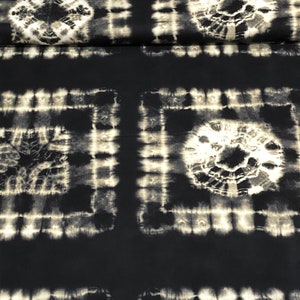 May include: Black and white tie-dye fabric with a repeating pattern of squares and circles. The fabric has a soft, textured feel.