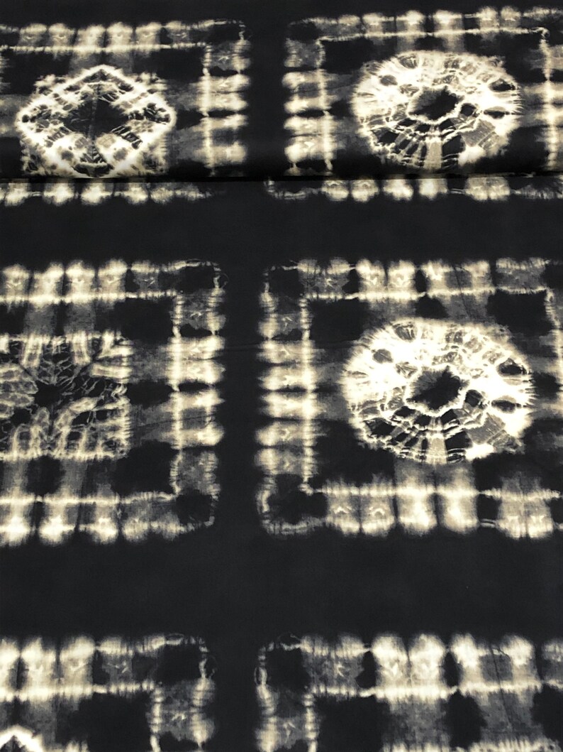 May include: Black and white tie-dye fabric with a repeating pattern of squares and circles. The fabric has a soft, textured feel.
