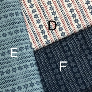 May include: Three fabric swatches with a repeating pattern of a rope design and a five-pointed star with the word "Sheriff" inside. The fabric swatches are in different colors: light blue, white with red stripes, and dark blue.