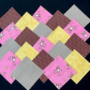 May include: A collection of 12 fabric squares featuring a pink and brown polka dot pattern, yellow squares with a white polka dot pattern, and pink squares with a monkey and banana design.