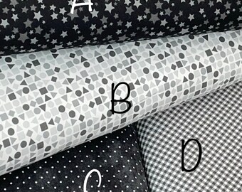 May include: Close-up of four fabric samples. A black fabric with white stars, a gray fabric with geometric shapes, a black fabric with white polka dots, and a black and white gingham fabric.
