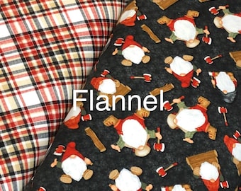 Peut inclure: Deux échantillons de tissu, l'un en flanelle à carreaux rouge et noir et l'autre en flanelle noire avec un motif répété de gnomes tenant des haches et des bûches.