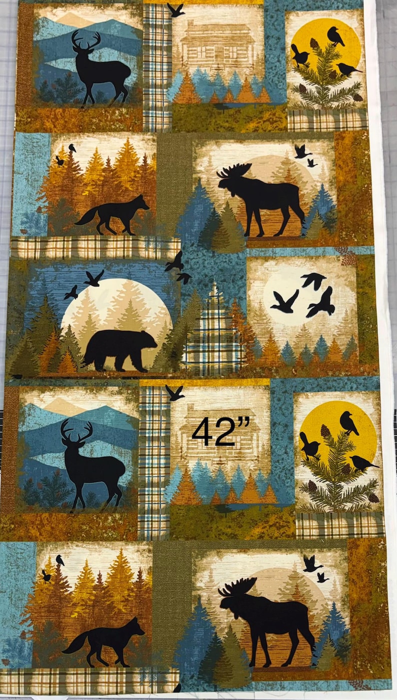 May include: Fabric panel featuring a patchwork design with woodland scenes. Each square depicts silhouettes of animals like deer, moose, and bears, along with trees and birds. The panel is 42 inches wide.