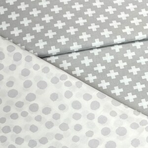 Puede incluir: Dos muestras de tela, una con un patr&oacute;n de cruz blanca sobre fondo gris y la otra con un patr&oacute;n de lunares blancos sobre fondo gris.