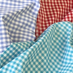 May include: Three gingham fabrics in blue, red, and turquoise colors. The fabrics are folded and layered on top of each other.