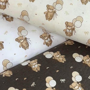 Pode incluir: Tecido com um padrão repetido de ursinhos de pelúcia castanhos segurando balões. Os ursos usam coletes e gravatas borboleta. As cores de fundo são branco, creme e castanho escuro. Pequenos laços e pontos estão espalhados pelo desenho.