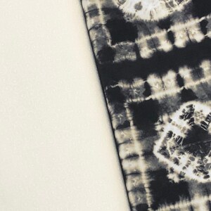 May include: Two fabric swatches, one white with a subtle pattern and the other black with a tie-dye pattern.