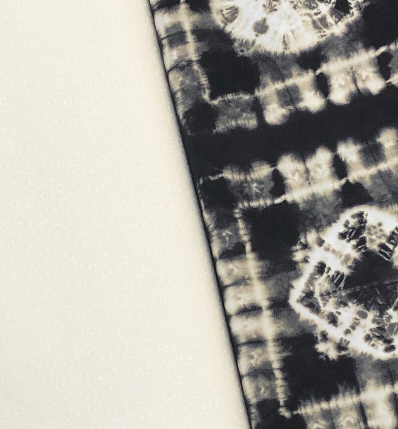 May include: Two fabric swatches, one white with a subtle pattern and the other black with a tie-dye pattern.