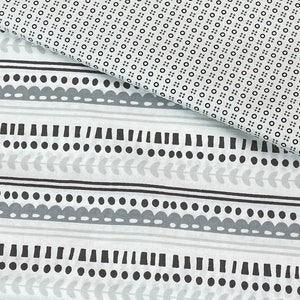 May include: A close-up of a white fabric with a repeating pattern of black circles and a gray and white striped pattern with black geometric shapes.