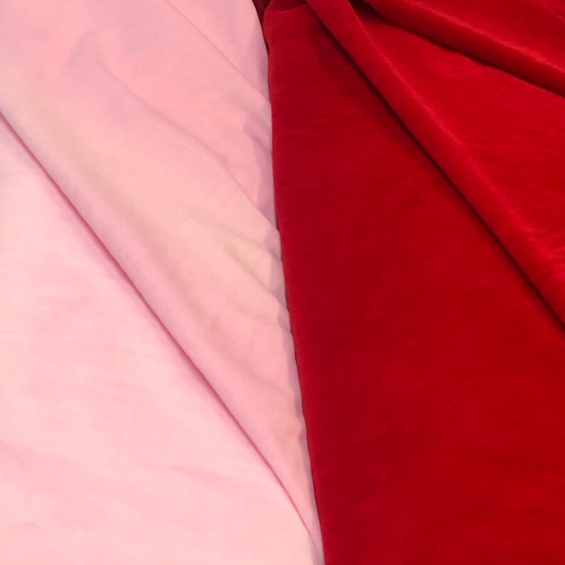 May include: Two fabric swatches, one pink and one red, are laid side by side. The pink fabric is smooth and the red fabric is textured.