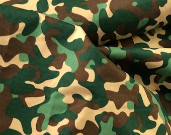 May include: Camouflage fabric with a green, brown, and beige pattern. The fabric is folded and has a textured surface.