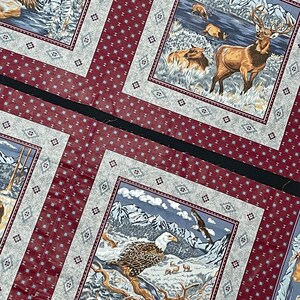 May include: A set of three fabric squares with a red and white patterned border. Each square features a different nature scene with a bald eagle, a deer, and a mountain range.