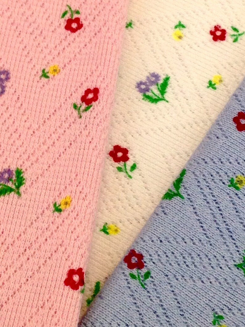 K&ouml;nnte beinhalten: Drei Stoffmuster mit einem Blumenmuster. Die Muster sind rosa, wei&szlig; und hellblau. Jedes Muster hat ein anderes Blumenmuster.