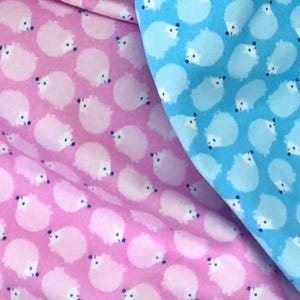 May include: Two fabric swatches with a repeating pattern of white hedgehogs on a pink and blue background.