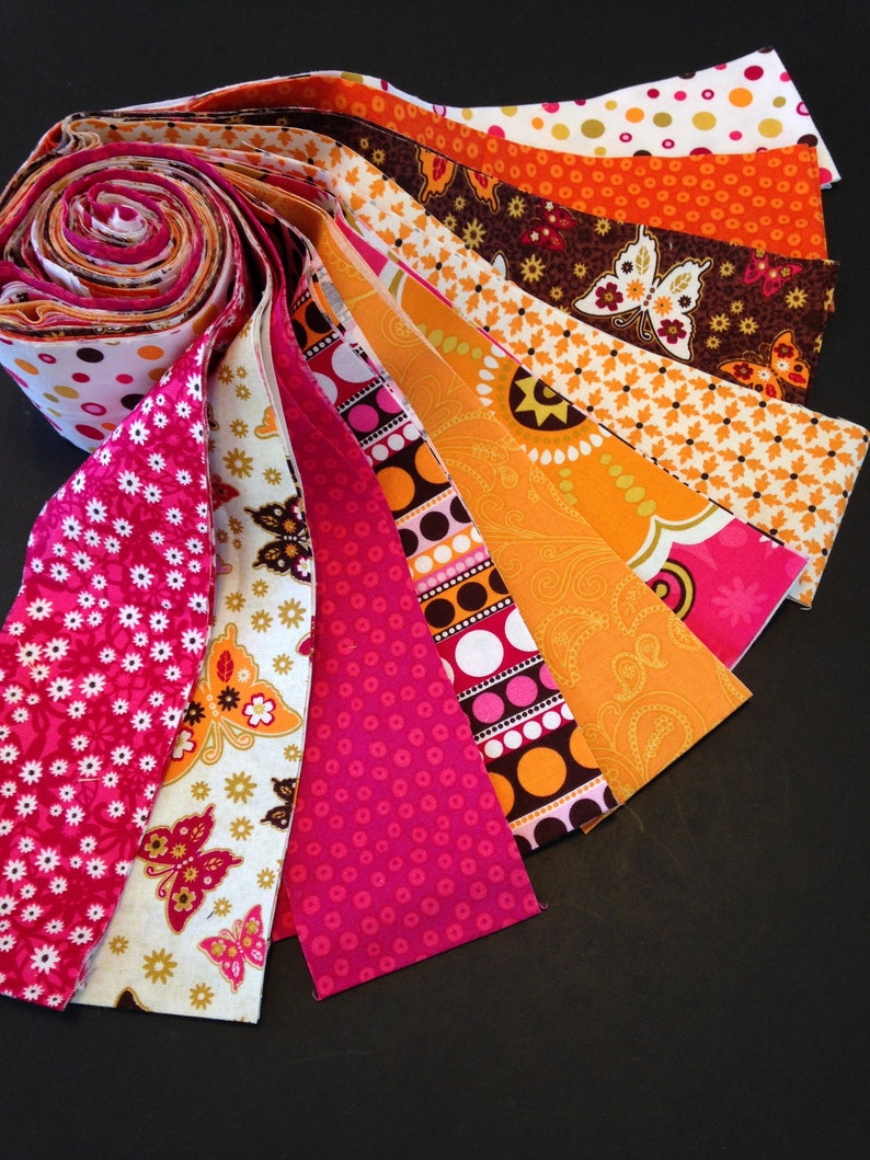 May include: A roll of fabric strips in various shades of pink, orange, and brown with different patterns, including polka dots, butterflies, and paisley designs.