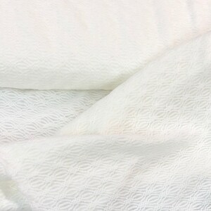May include: White fabric with a delicate, embossed pattern. The fabric has a soft, textured surface and a subtle sheen.