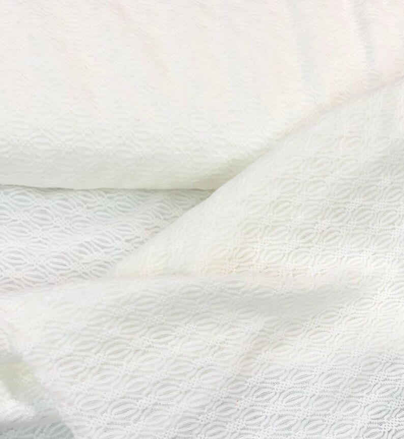 May include: White fabric with a delicate, embossed pattern. The fabric has a soft, textured surface and a subtle sheen.