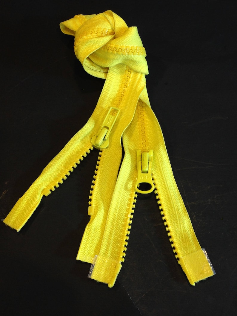 May include: Three yellow zippers with metal sliders. The zippers are knotted together at the top.