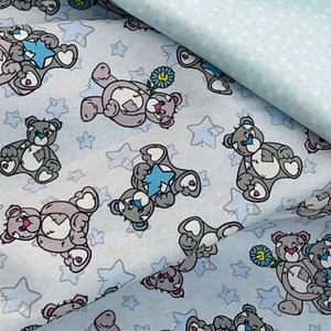 May include: Blue fabric with a repeating pattern of grey teddy bears holding stars and flowers. The background is a light blue with white polka dots.