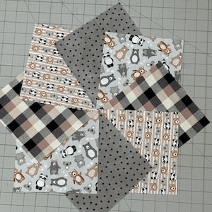 May include: Eight square fabric swatches arranged in a circular pattern. The patterns include black and white panda faces on striped backgrounds, grey fabric with black polka dots, brown and black buffalo plaid, and grey fabric with bear motifs.
