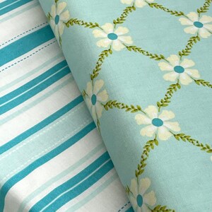 May include: Two fabric swatches, one with a blue and white striped pattern and the other with a light blue background and a white floral pattern.