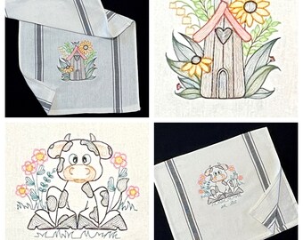 May include: Set of four embroidered kitchen towels. One towel features a cartoon cow with black and white spots surrounded by flowers. Another towel features a small house with a heart-shaped window and flowers. The remaining two towels have black and white stripes.
