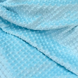 May include: A close-up of a light blue fabric with a textured pattern of small raised dots. The fabric is soft and plush, and it has a subtle sheen.